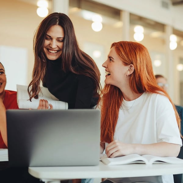 Two women laughing Infront of a laptop