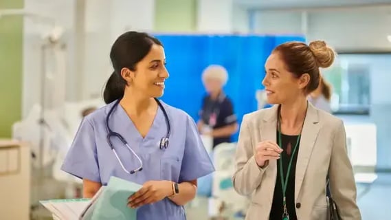 A smiling hospital director speaking with a healthcare practitioner about patient care and wellfare.