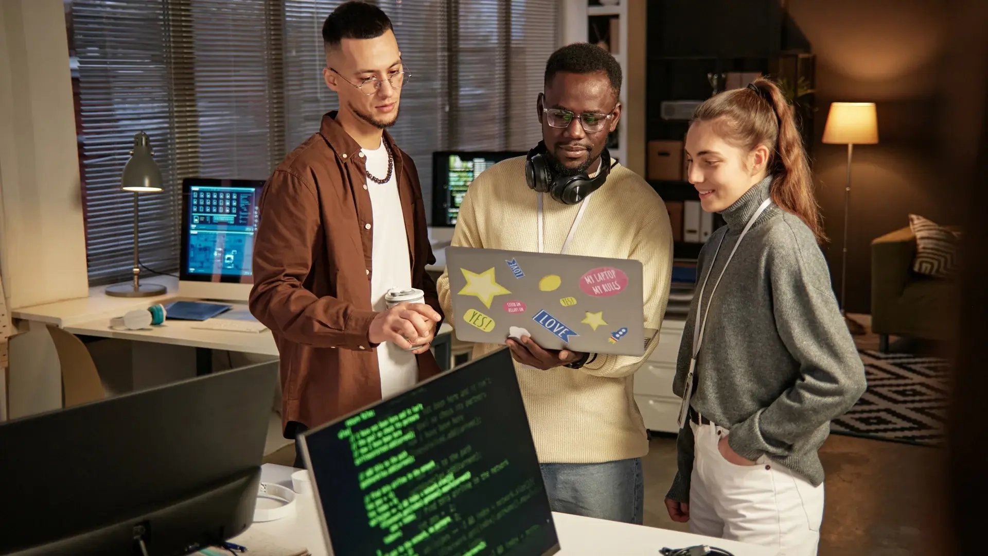 Group of software developers in casual clothes concentrating on programming with a laptop.