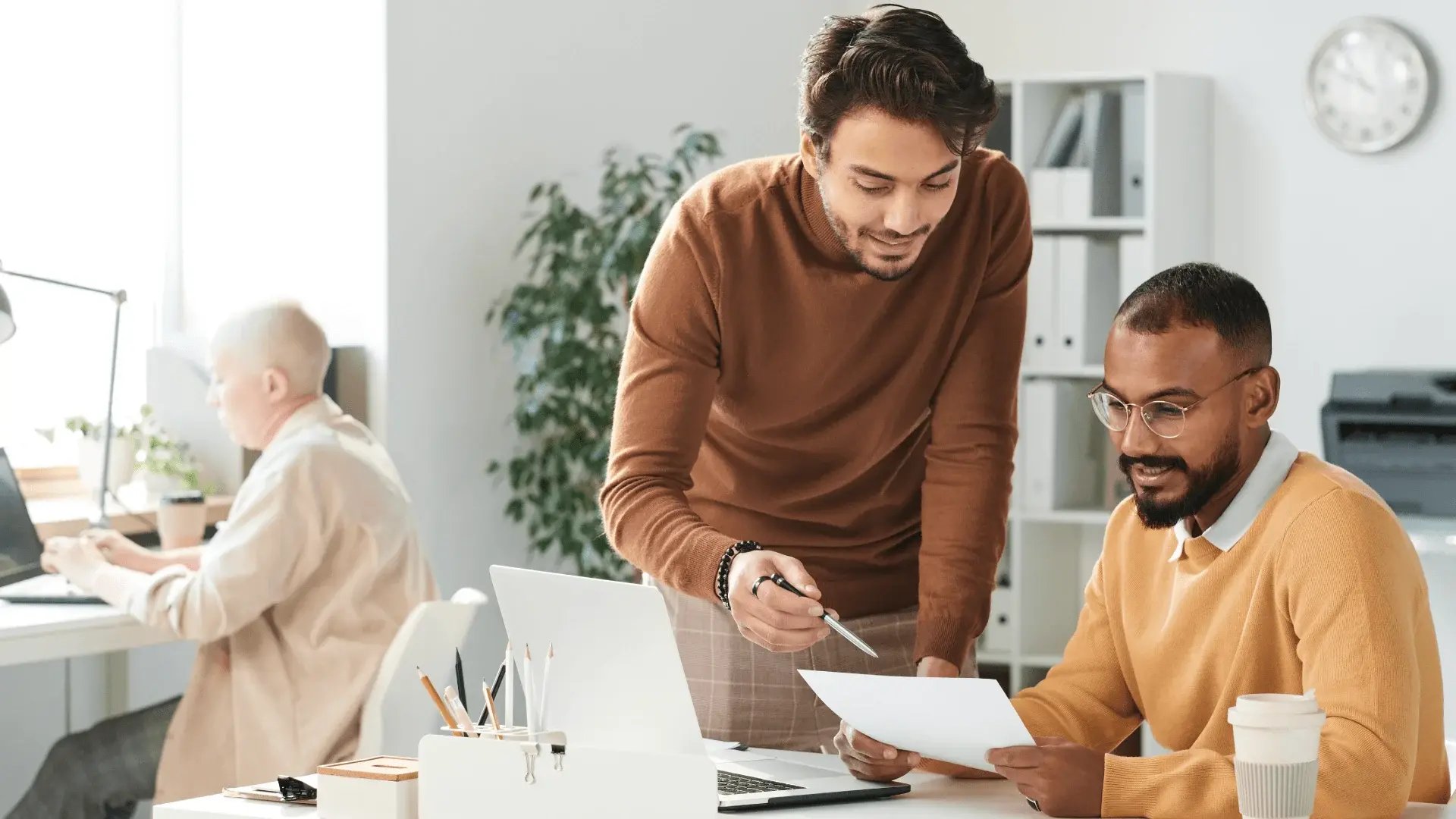 Male student in office showing another person the skills developed on their part-time course.