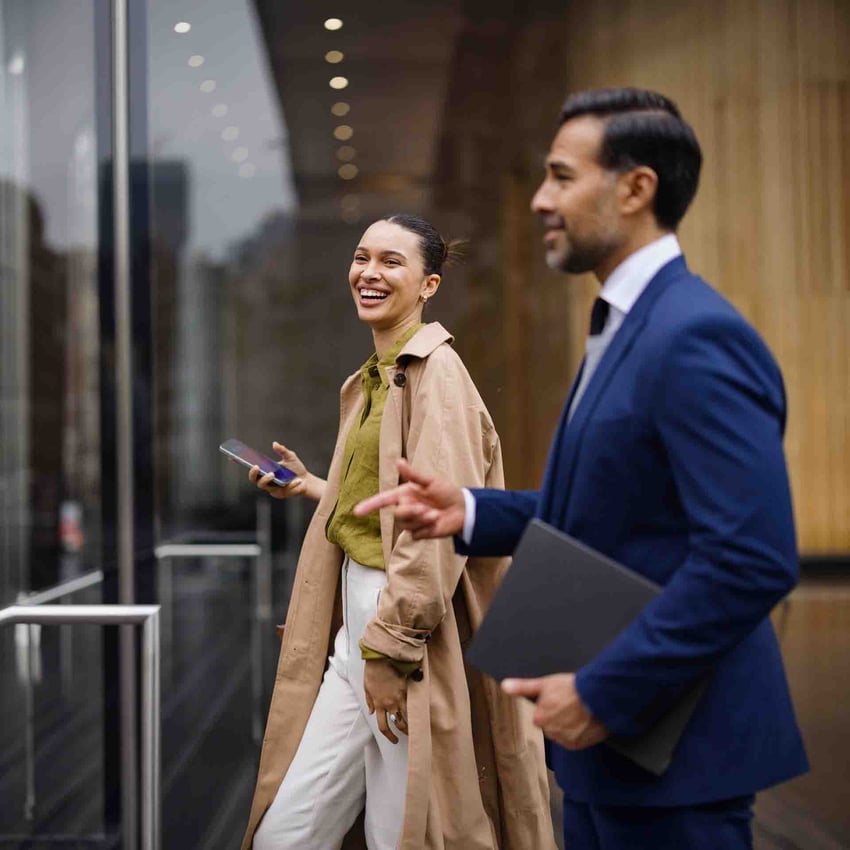 Two coworkers walking together and chatting in a corporate environment