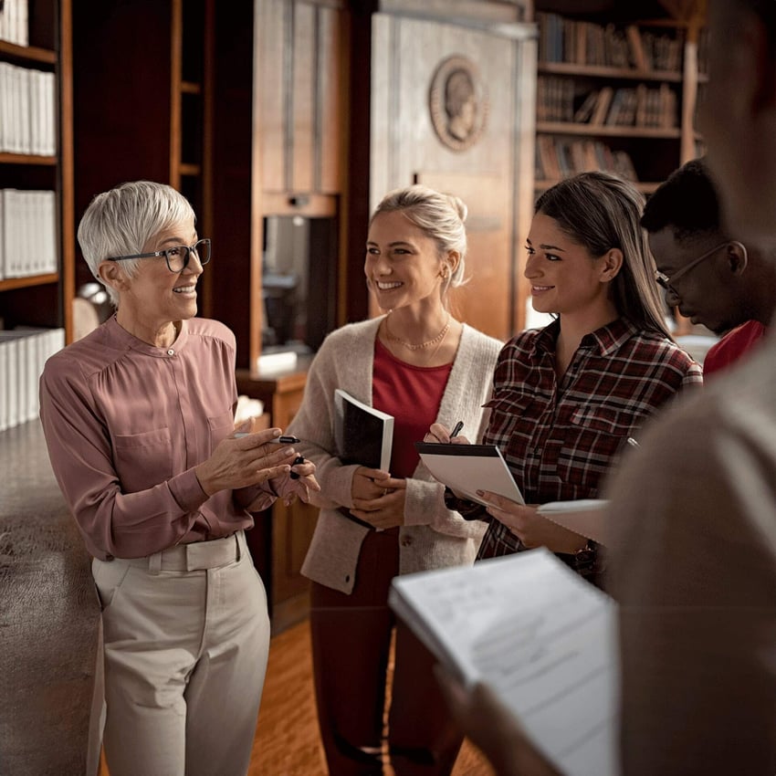 A group of business women standing together in an office, smiling and discussing.