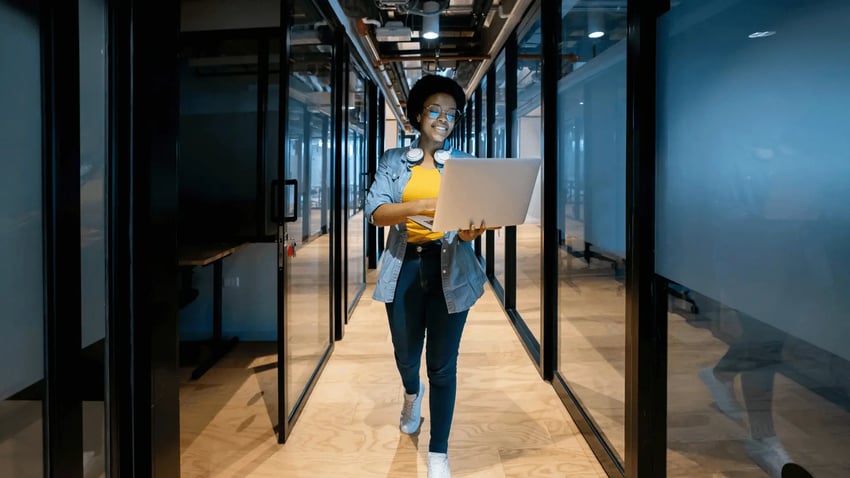 Woman with laptop walking down hallway