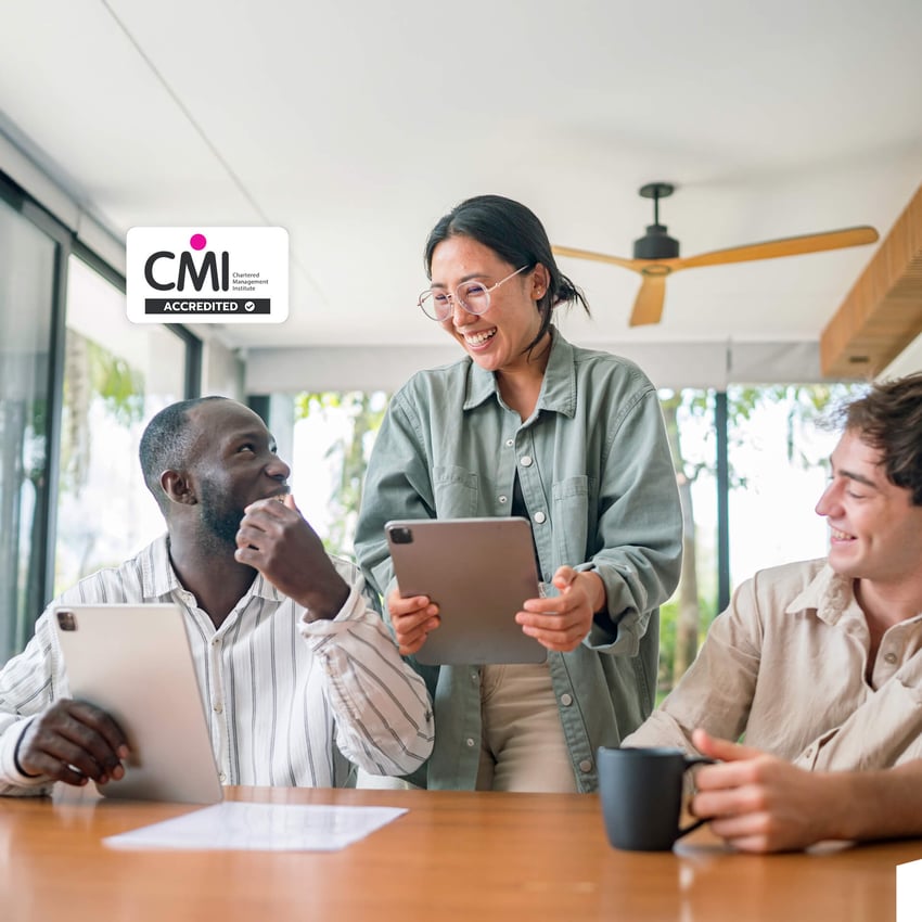 A group of professionals in a workplace discussing documents, representing students studying an MBA Human Resource Management online.