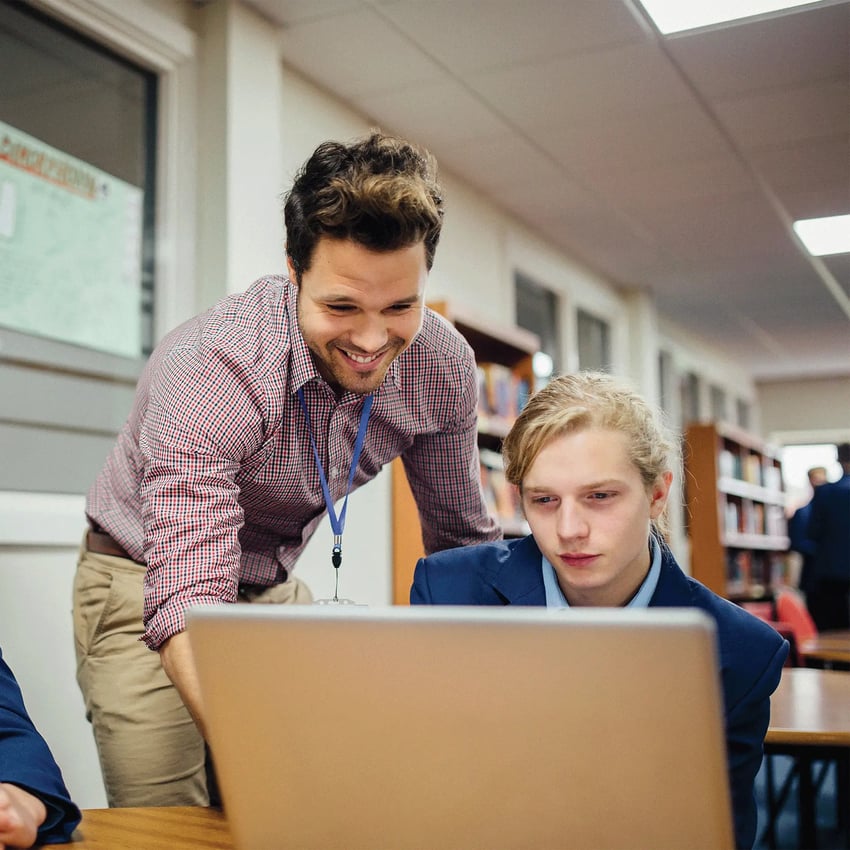 A teacher helping a student on his laptop.