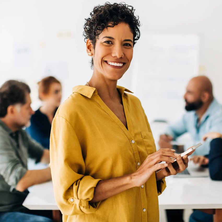 A woman holding her phone and smiling.