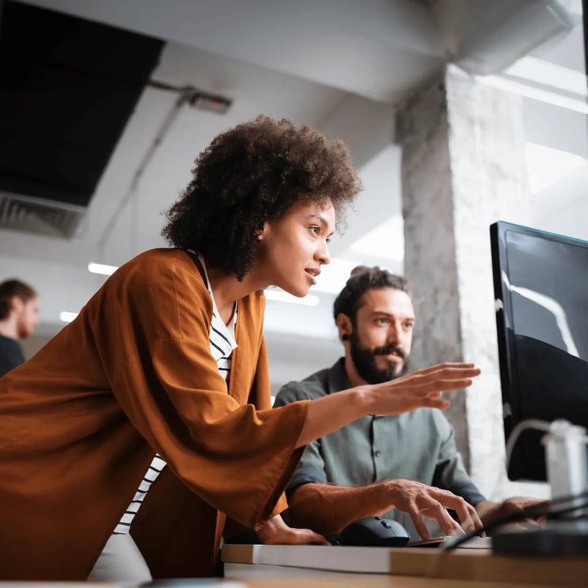 Two professionals in a modern office are looking at a computer screen, the woman has her arm reached out eagerly towards the monitor looking enthusiastic about the CSCF.