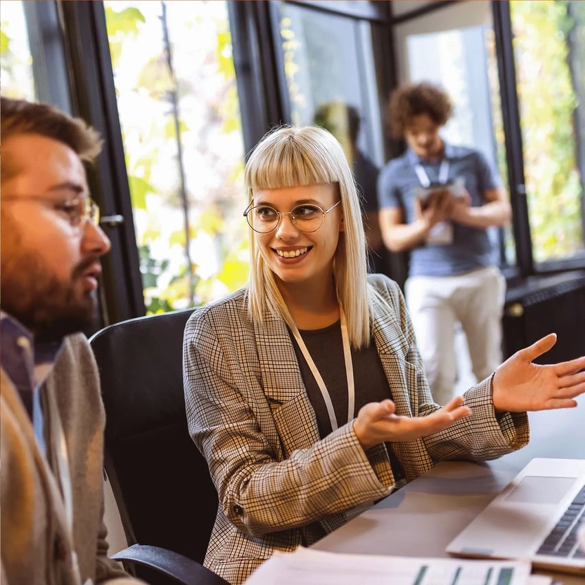 Blonde woman with glasses discussing recognition of prior learning in the UK at an event.